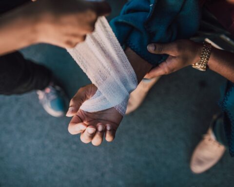 Iemand legt een verband aan rond een gekwetste pols, buiten