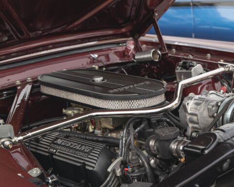Geopende motorkap van een klassieke auto met de motor en de hulpaggregaten in beeld